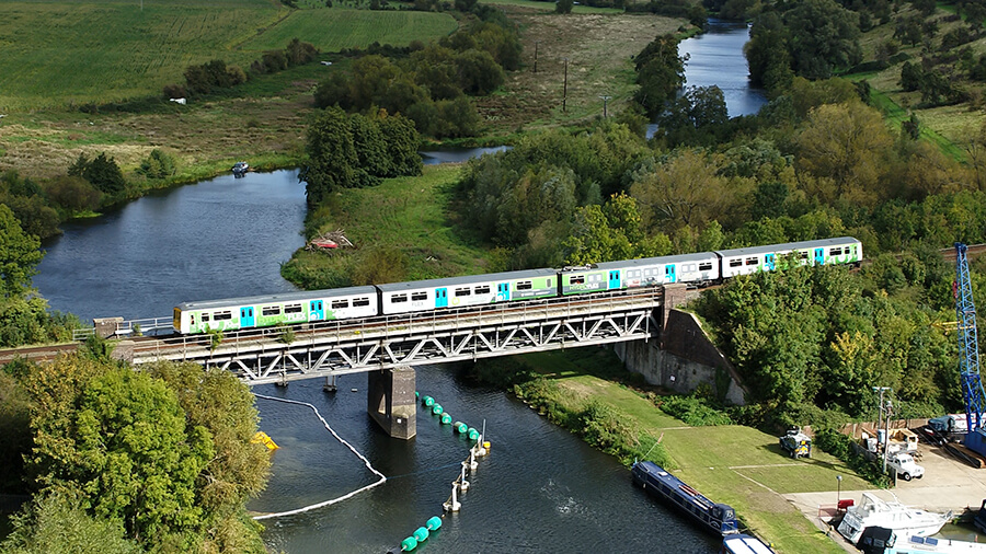Drone shot of hydroflex hydrogen-powered train crossing a railway bridge
